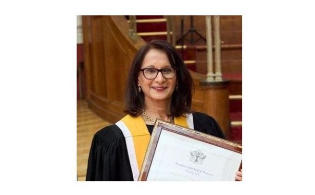 Professor Shahina Pardhan holds up her framed award.